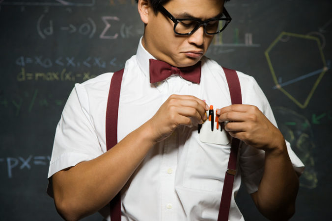 Nerdy Asian male student adjusting pencils in pocket