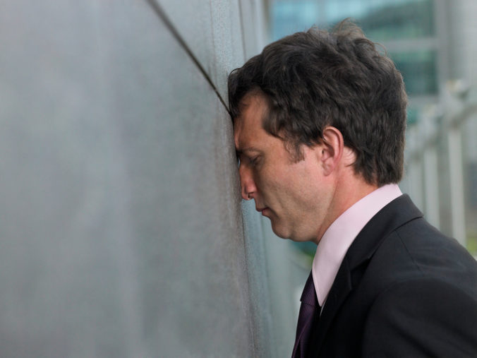 Businessman with face pressed against wall, profile, close up