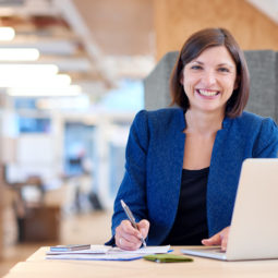 Busineswoman smiling broadly while working in her office cubicle