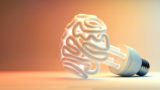 An illuminated fluorescent light bulb in the shape of a stylized brain on an isolated colorful studio background