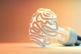 An illuminated fluorescent light bulb in the shape of a stylized brain on an isolated colorful studio background