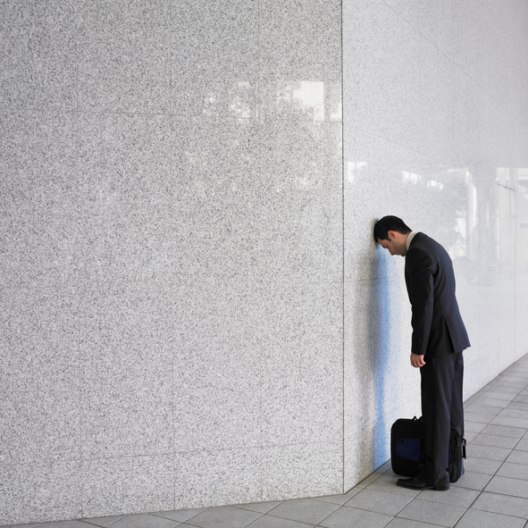 Businessman leaning head on wall