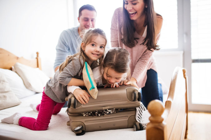 Portrait of a young happy family with two children packing for holiday at home.