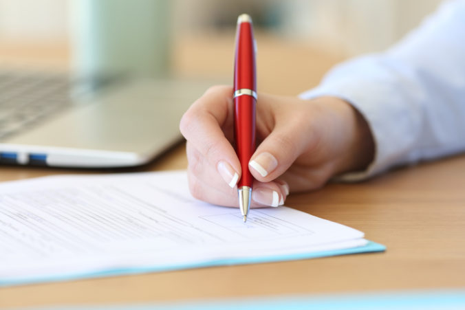 Businesswoman hand signing a contract on a desk