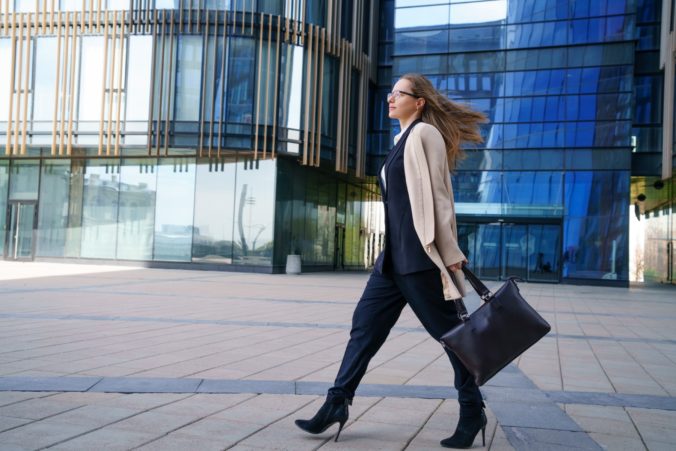Business woman in a coat and suit goes near the business