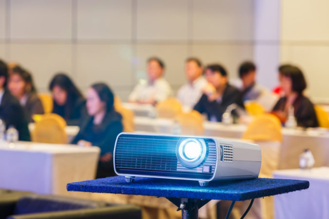 Close,Up,Projector,In,Conference,Room,With,Blurry,People,Background