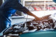 Car mechanic holding clipboard and checking to maintenance vehicle by customer claim order in auto repair shop garage. Engine repair service. People occupation and business job. Automobile technician