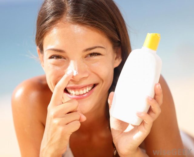 Woman smiling holding bottle of sunsreen.jpg