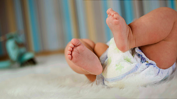 Newborn baby in diaper lying on plush blanket
