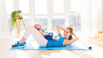 Sports mother is engaged in fitness and yoga with baby at home
