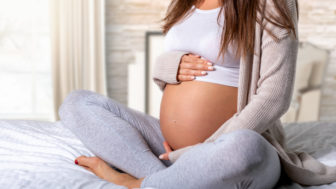 Closeup of a pregnant woman sitting on the bed