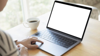 Women using laptop with blank screen at table in the office.