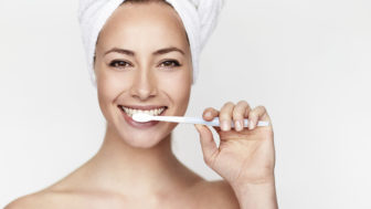 Beautiful young woman brushing teeth, portrait