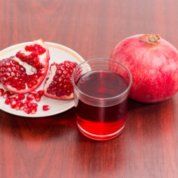 Pomegranate juice in glass, whole and part of split pomegranate