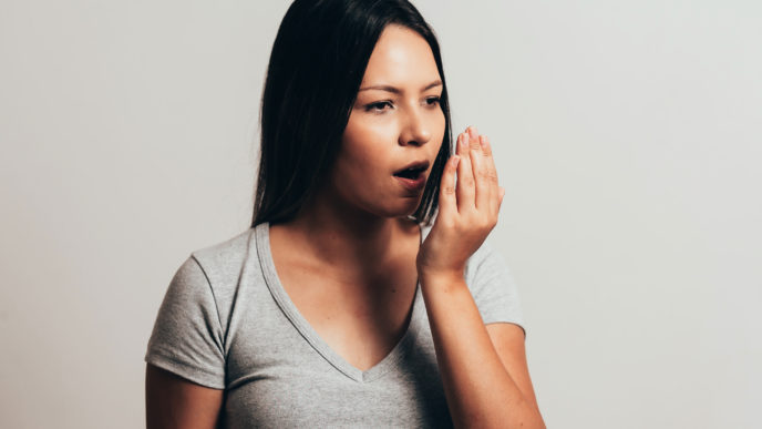 Bad breath. Halitosis concept. Young woman checking his breath with his hand.