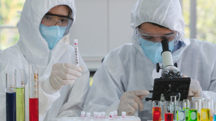 Coronavirus covid 19 infected blood sample in sample tube on hand of scientist in biohazard protection clothing doing analysis to virus sample in laboratory