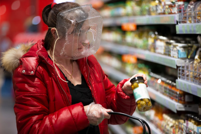 Coronovirus protection. Woman in a store with a plastic box on her face. A funny way to protect against COVID 19.Coronavirus and panic buying concept