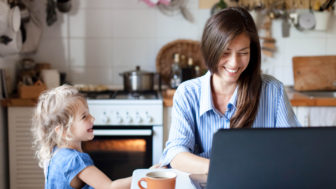 Working mom works from home office. Happy mother and daughter smiling. Successful woman