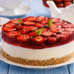 Homemade strawberry cheesecake on blue wooden background.