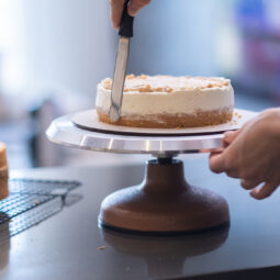 Skilled self made confectioner smearing white cream around cake layer made of lactose free products