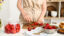 Woman cutting fresh berries for preparing sweet strawberry jam at table in kitchen