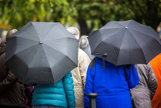 Návštevníci mesta s dáždnikmi v upršanom jesennom počasí na Námestí slobody.