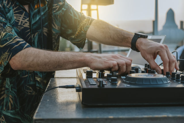 Close up of the hands of a DJ playing music on a terrace
