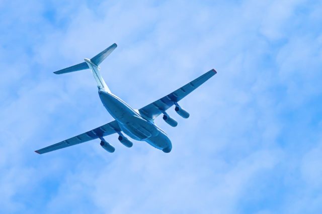 Airplane in blue sky. Air cargo transportation. Plane is flying