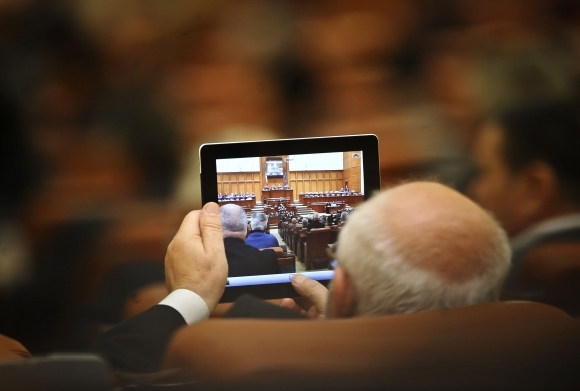 Rumunský poslanec sa na seba pozerá cez tablet