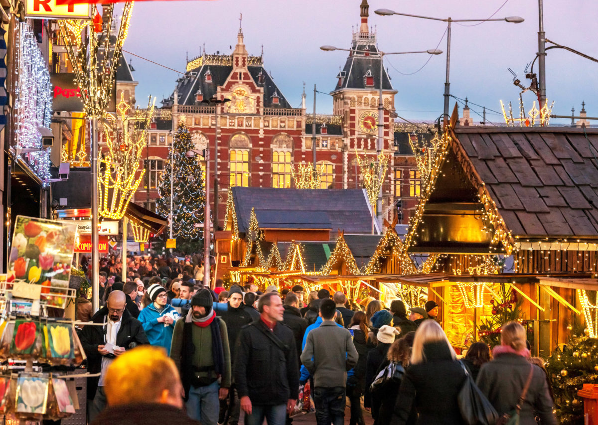Amsterdam Christmas Market on the Damrak from the Central Station to the Dam Square. Rush hour with tourists and commuters.