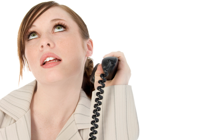 Close up of a businesswoman holding a telephone receiver and looking up