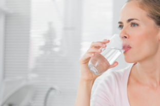 Pensive blond woman drinking water