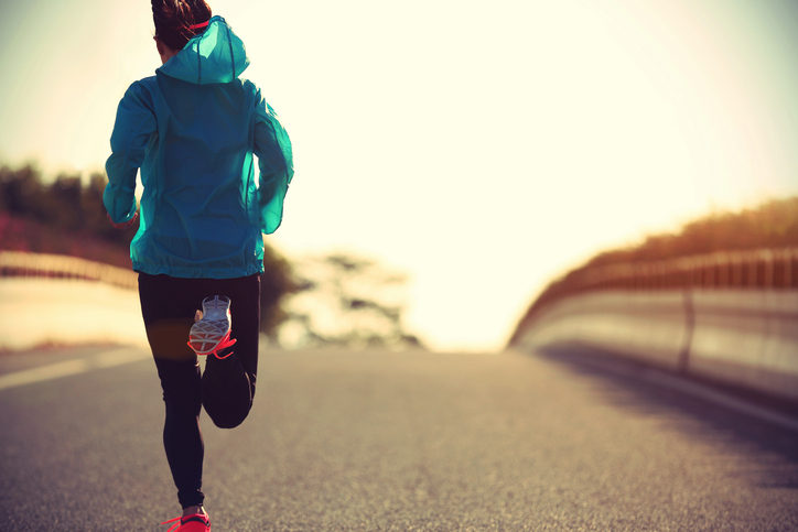 Young fitness woman runner running on sunrise road