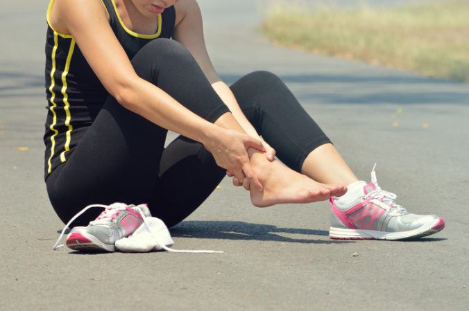 Young woman suffering from an ankle injury while exercising and