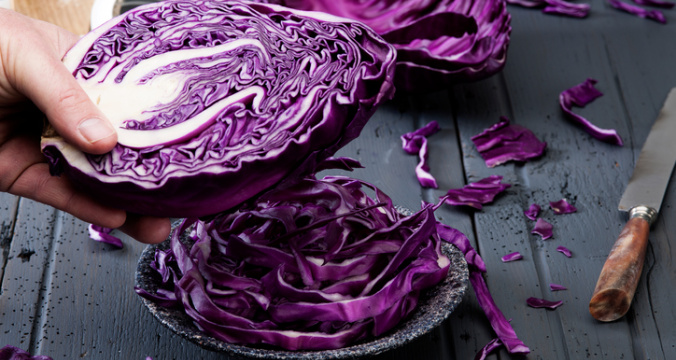 Chopped red cabbage on old wooden table with half cabbage