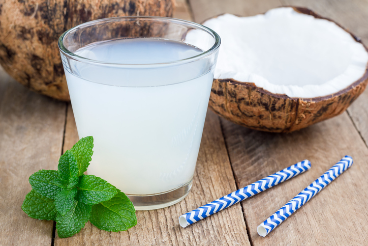 Coconut drink with pulp in glass on wooden table