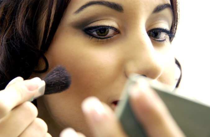 Close up of a young woman putting on makeup