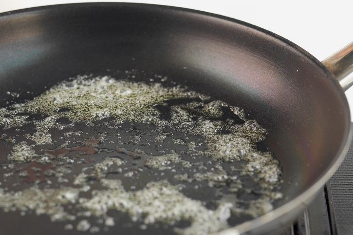 Butter melting and frying in a pan, close up