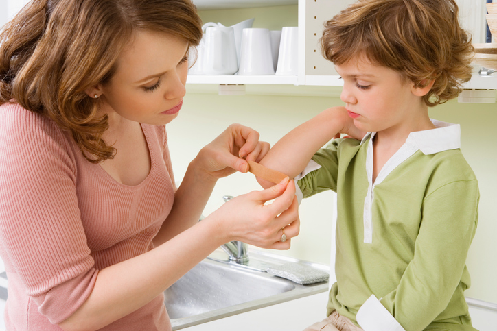 Mother putting bandage on daughter's cut
