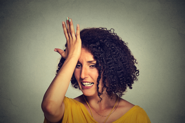 Woman slapping hand on head to say duh made mistake