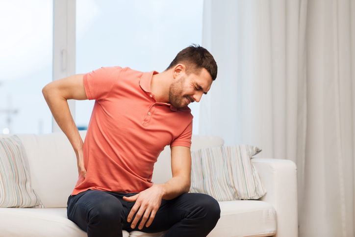 Unhappy man suffering from backache at home