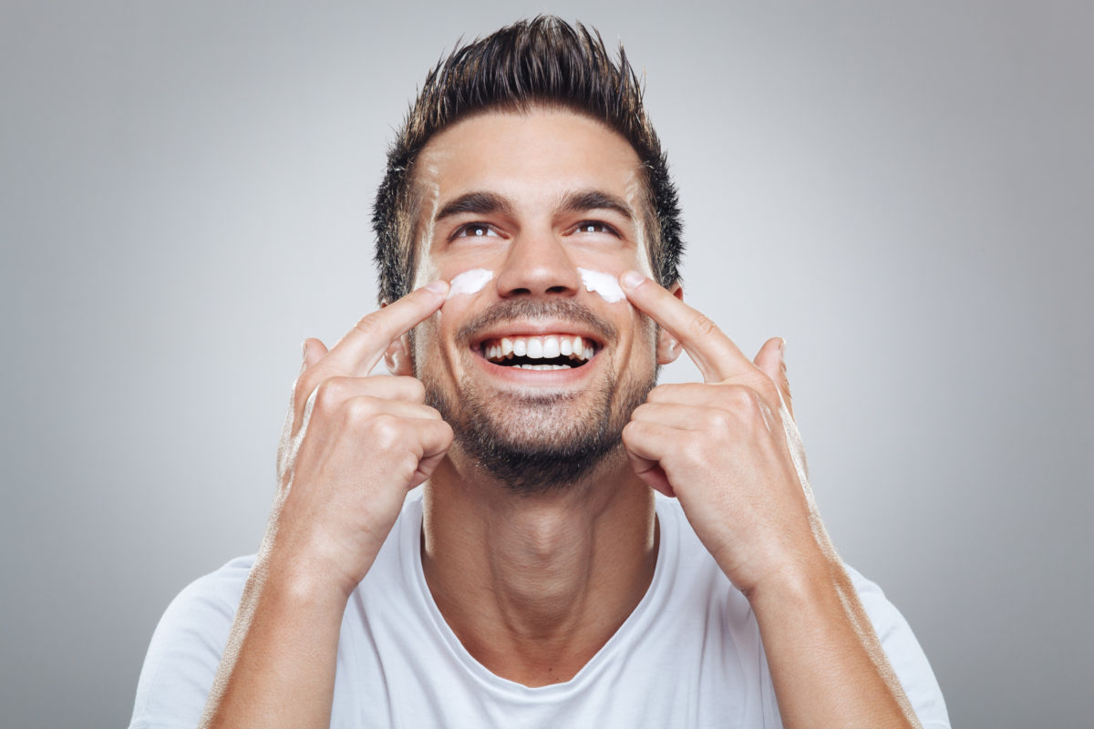 Young man with moisturizer on the face