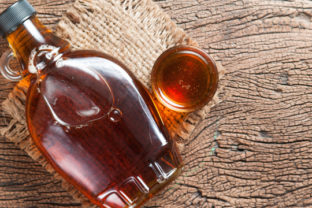 Maple syrup in glass bottle on wooden table