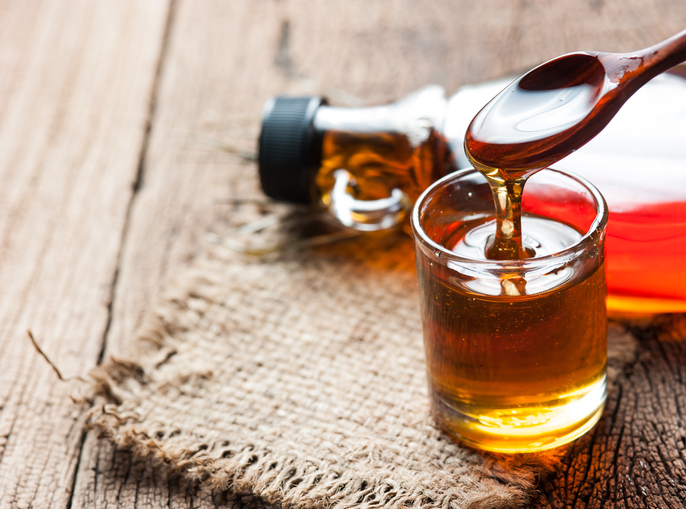 Maple syrup in glass bottle on wooden table