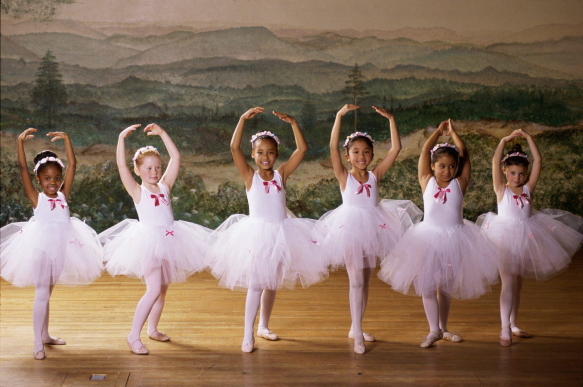 Group of ballet dancers dancing with their arms raised