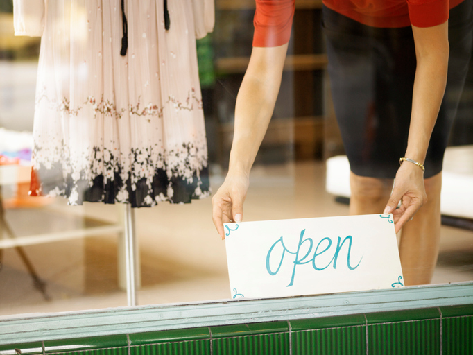 Boutique salesperson placing open sign on window