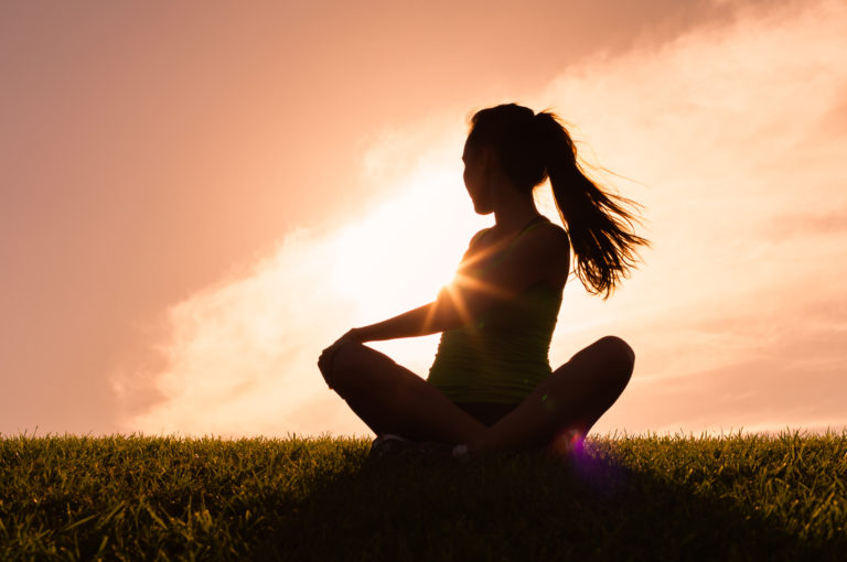 Female doing yoga stretches against a beautiful sunset.