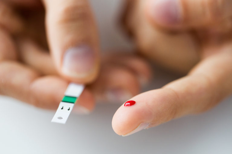 Close up of male finger with blood and test stripe