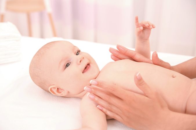 Mother hands applying cream on baby after bathing in room