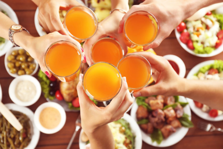 Friends cheering with glasses of orange juice in restaurant